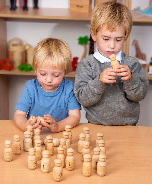 Two children playing with little wooden alphabet figures